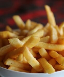 Delicious crispy golden french fries served in a white bowl, perfect for a tasty snack.