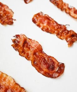 High-quality food photography of crispy bacon slices arranged on a white background.